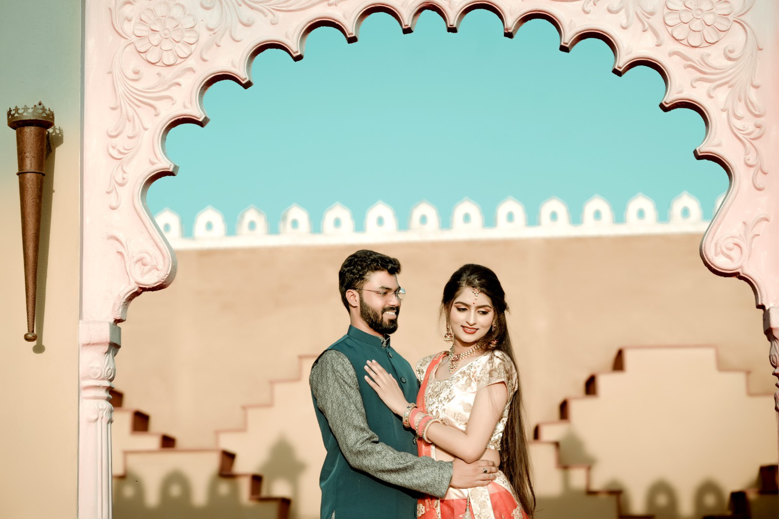 Pre-wedding couple embracing under a scalloped pink archway