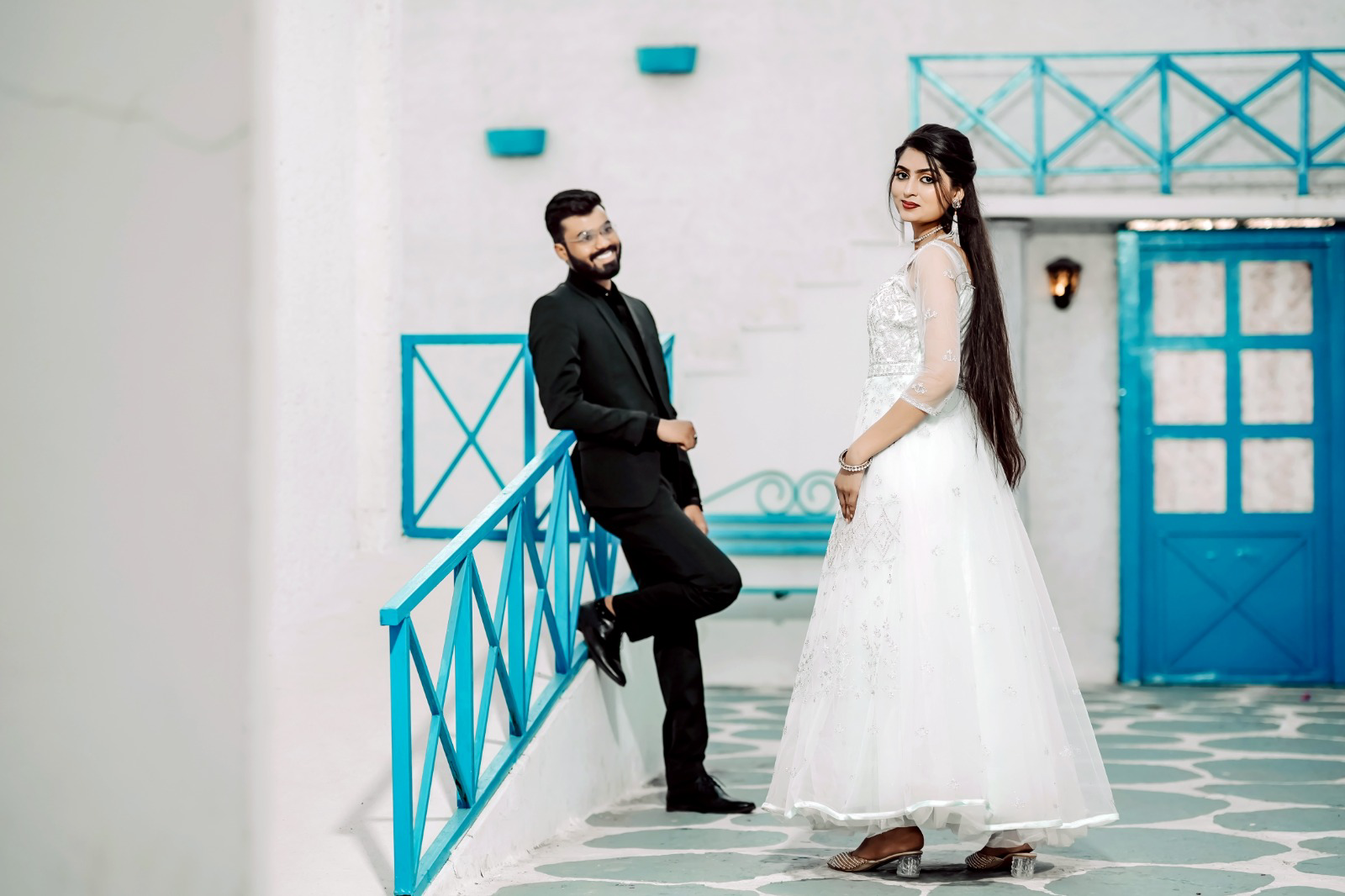 Pre-wedding couple in white and black outfits against a blue-and-white setting